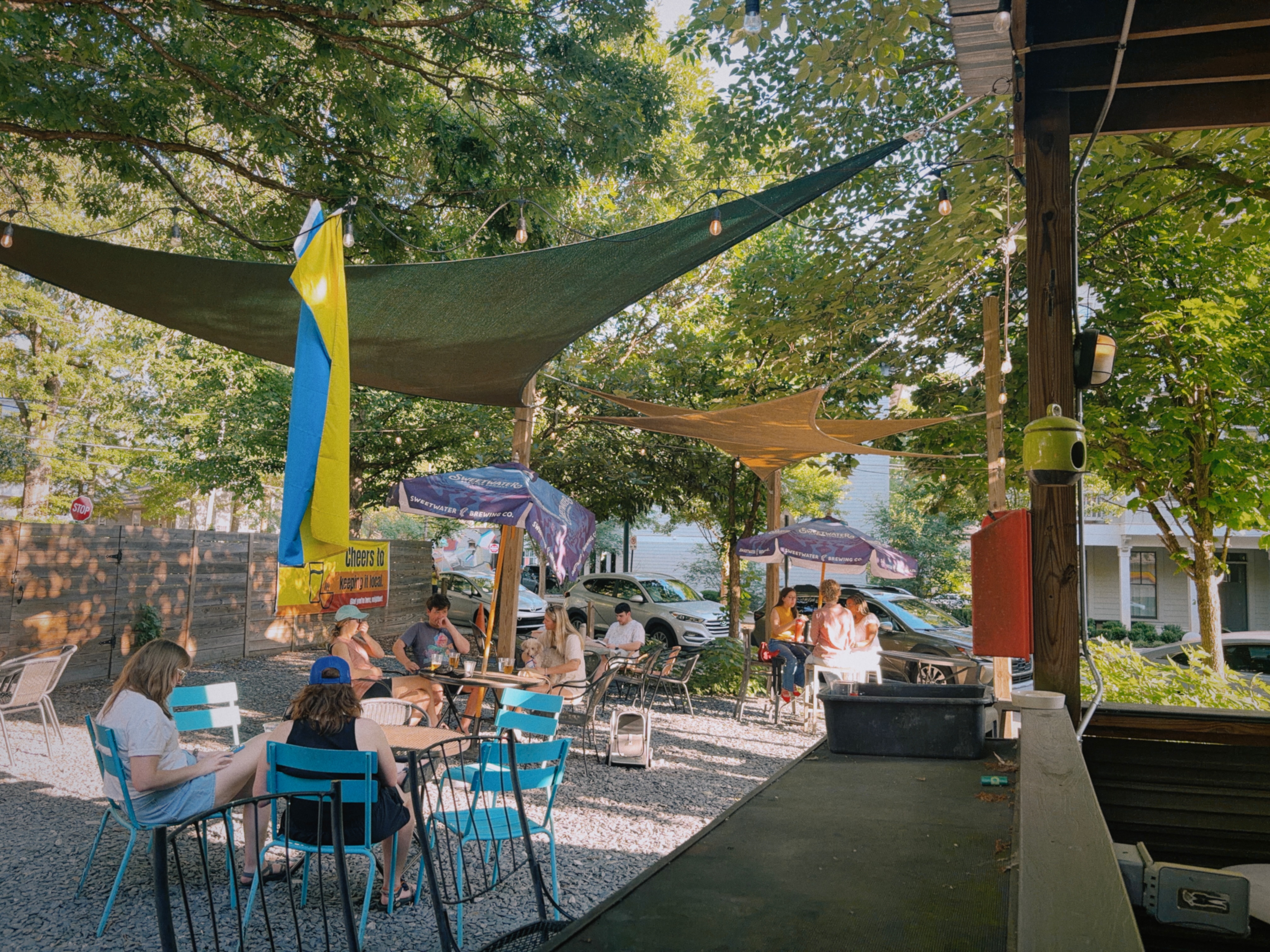 The Parkgrounds patio — shade sails, string lights, and a neighborhood crowd settled in for the afternoon.